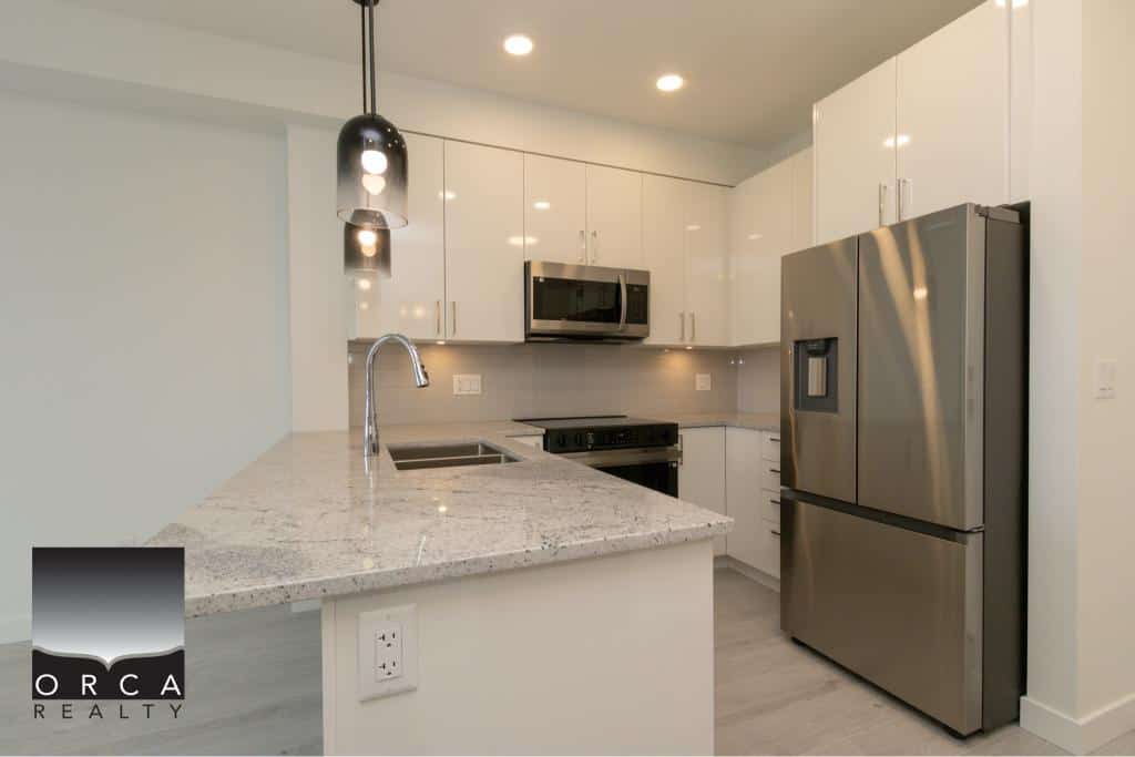 Modern kitchen with stainless steel appliances, granite countertops, Contemporary white cabinets, and sleek black pendant lighting, showcasing a stylish and functional space perfect for urban living.