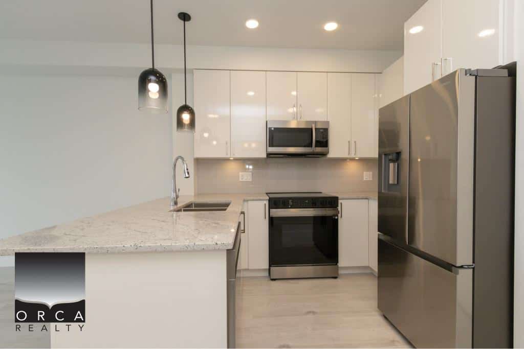 Modern stainless steel kitchen appliances in a bright, contemporary home, featuring sleek white cabinetry, granite countertops, and energy-efficient lighting—ideal for Vancouver real estate.