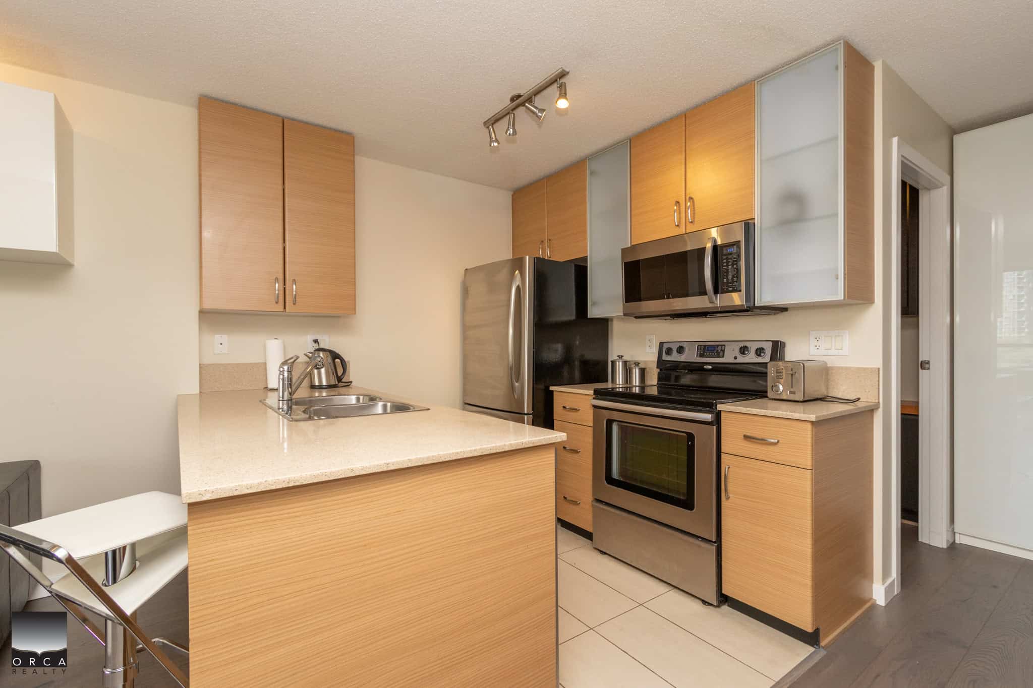 Modern kitchen with stainless steel appliances, light wood cabinets, and beige countertops, perfect for Vancouver Island living.