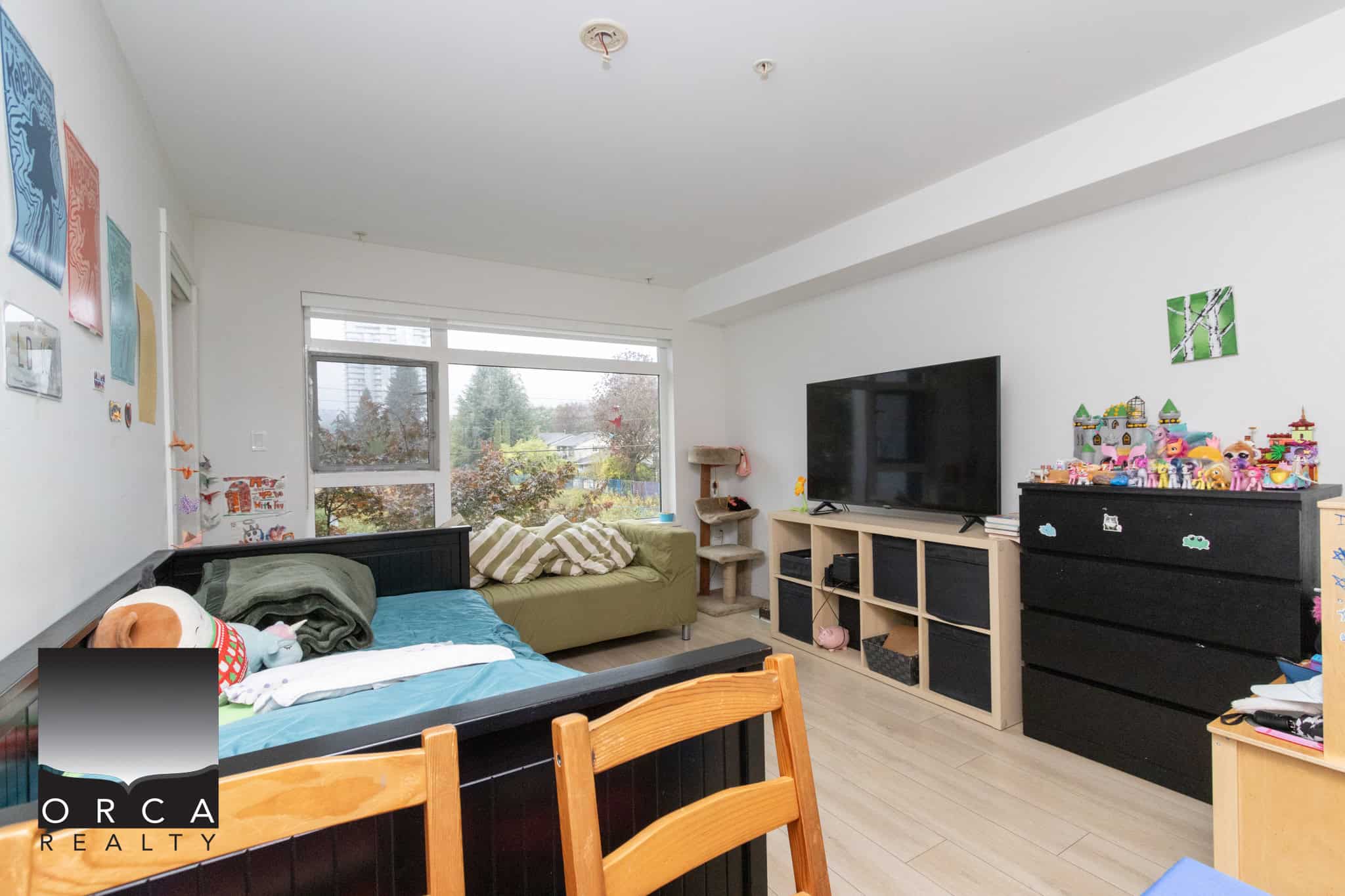 Bright living room with large window, modern decor, and TV setup, showcasing a cozy space for family entertainment in Vancouver.