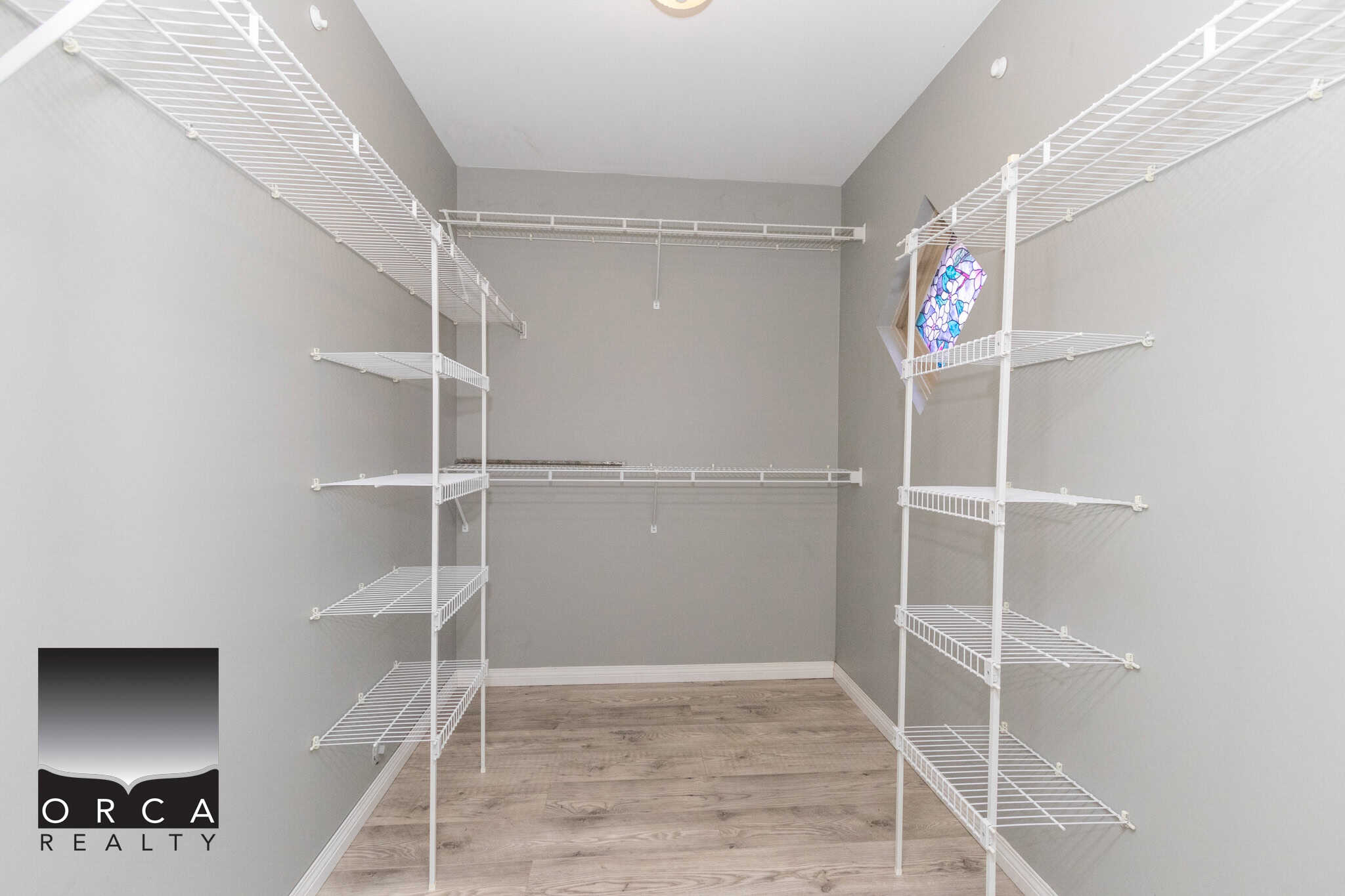 Spacious walk-in closet with white wire shelving and light grey walls for organized storage; ideal for modern homes in Victoria, BC market.