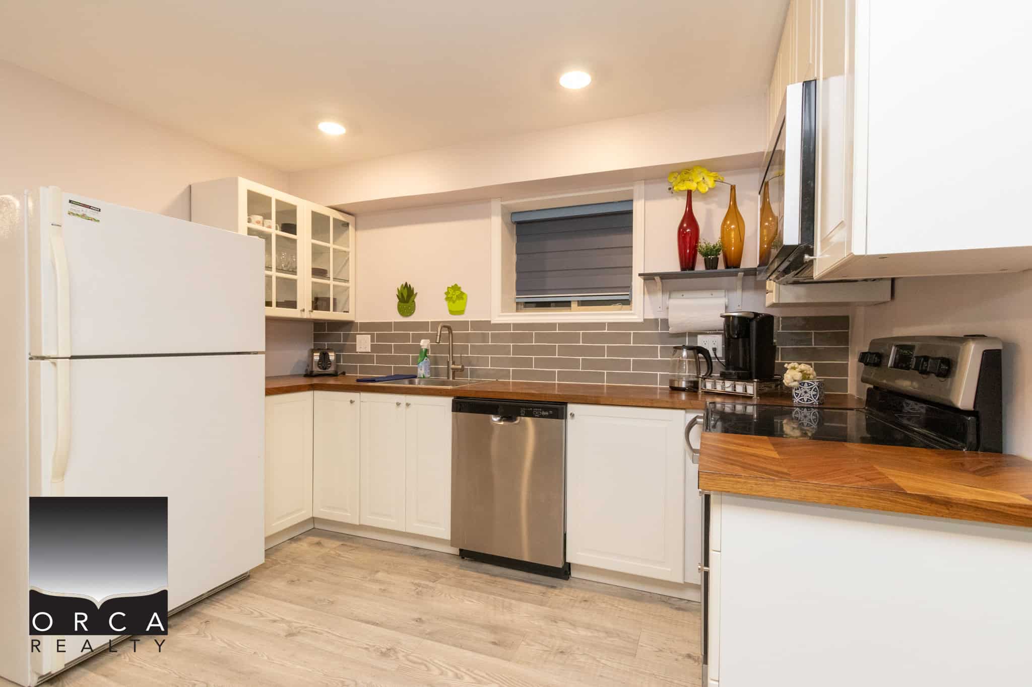 Bright modern kitchen with white cabinets, stainless steel appliances, grey tile backsplash, and ample counter space; perfect for homebuyers seeking stylish and functional Vancouver area homes.