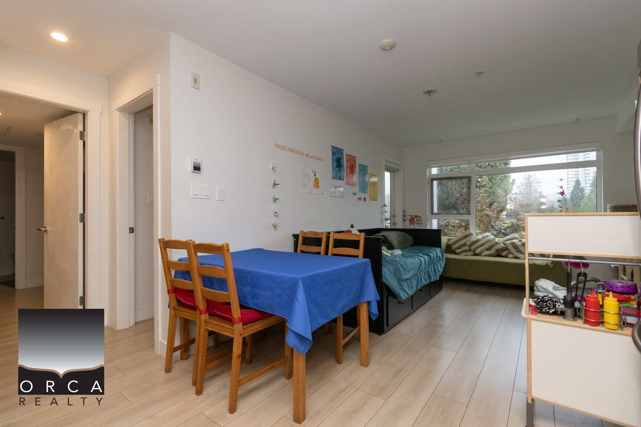 Bright open-concept living and dining area with large windows, hardwood floors, and casual furniture, showcasing a welcoming space ideal for family gatherings and entertaining.