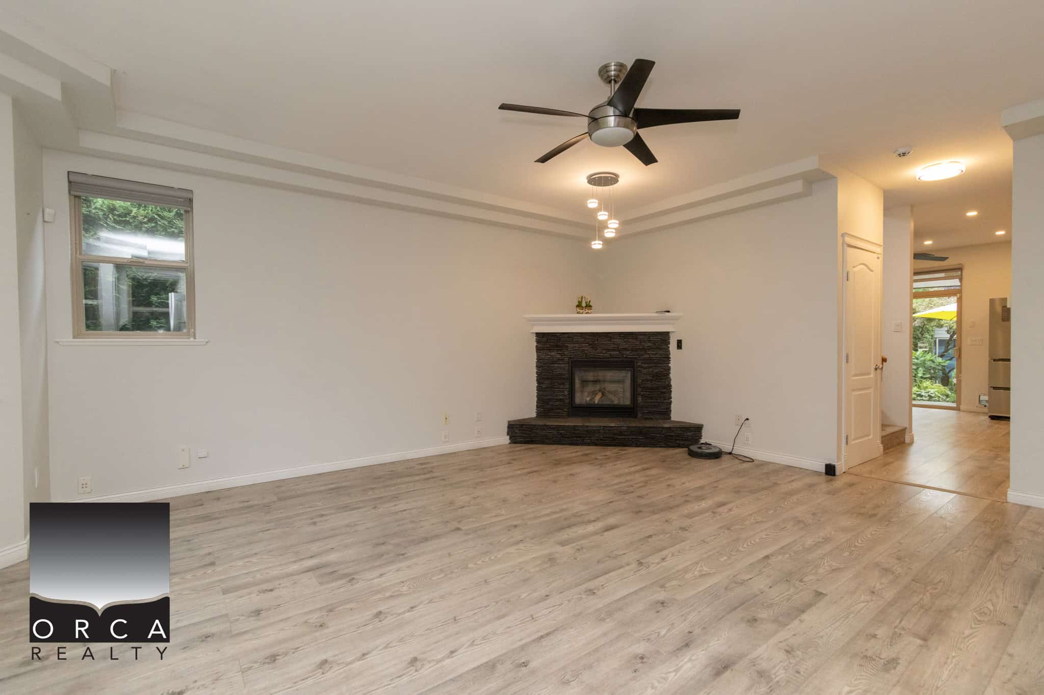 Modern living room with minimalist design, white walls, wood flooring, and a sleek black fireplace with a white mantel, ideal for Vancouver Island homes.