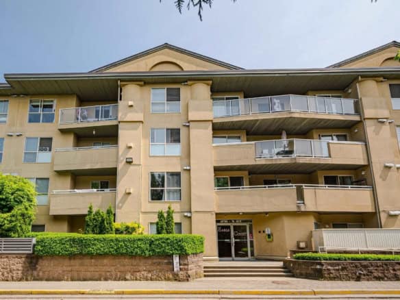 Spacious multi-family residential apartment building with multiple balconies, surrounded by lush greenery, in a well-maintained neighbourhood in British Columbia.