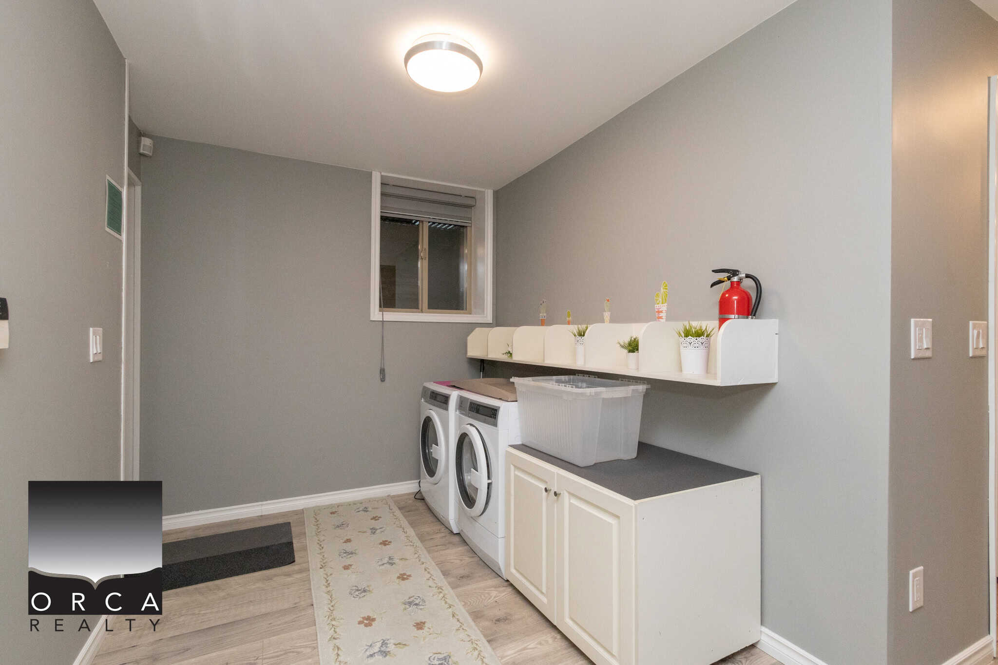 Bright laundry room with washer and dryer, white cabinetry, and neutral grey walls, perfect for home organization and utility.