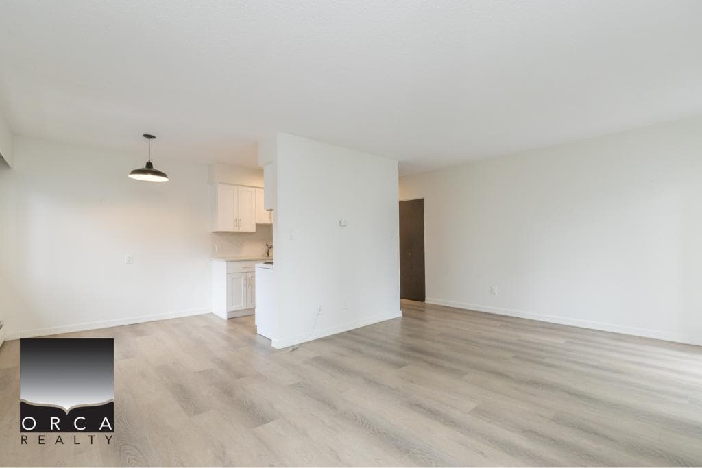 Bright open living space in a modern apartment with light wood flooring and white walls, ideal for homebuyers and investors seeking Vancouver real estate opportunities.