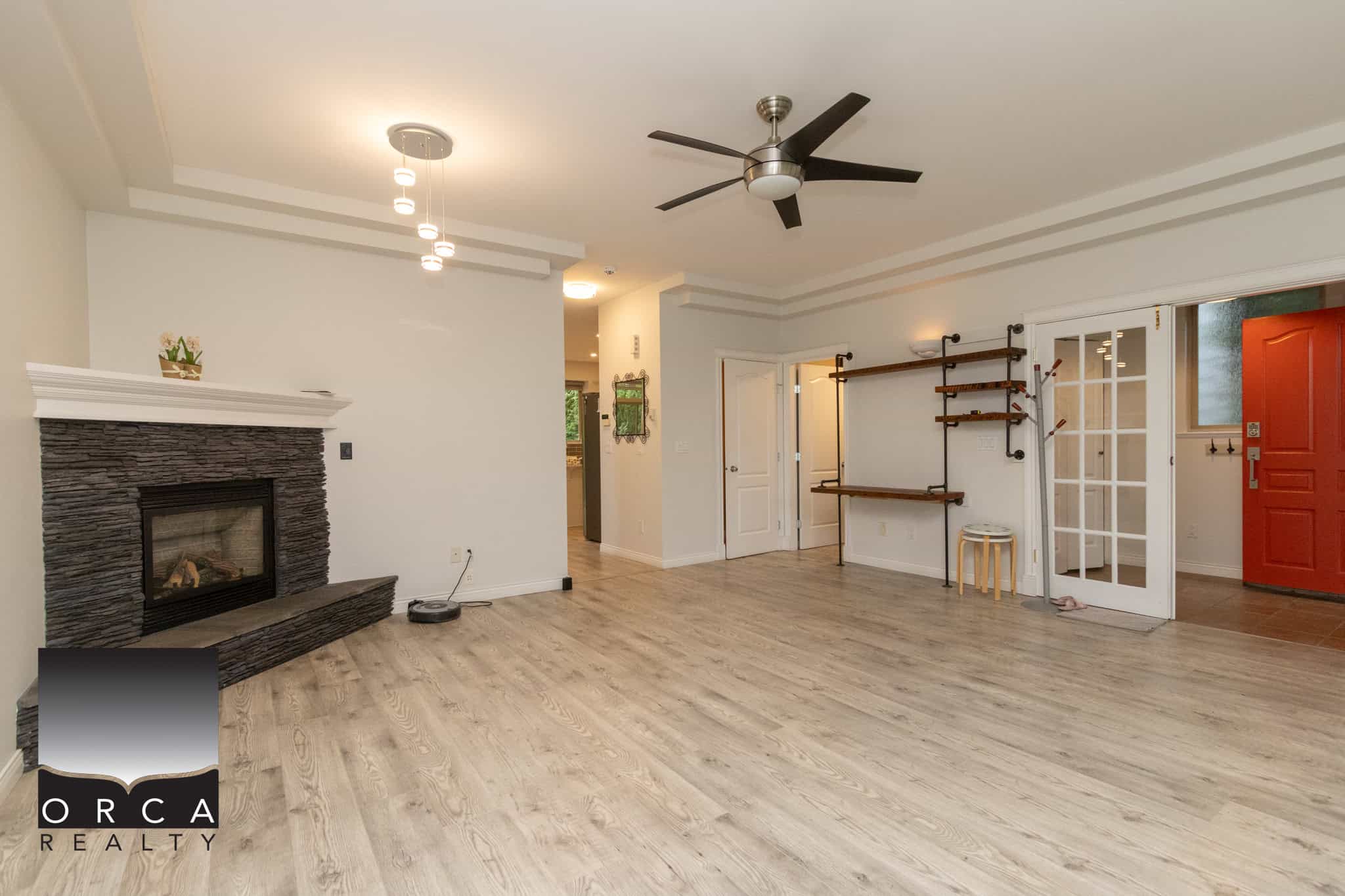 Bright spacious living room with modern decor, fireplace, and ceiling fan, ideal for Vancouver Island real estate viewing, by Orca Realty Inc.