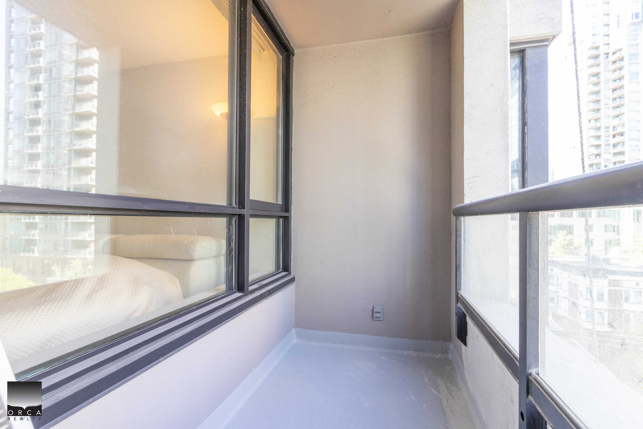 Bright urban apartment balcony with glass railing, offering outdoor space and city views, ideal for relaxing or enjoying Vancouver’s skyline.