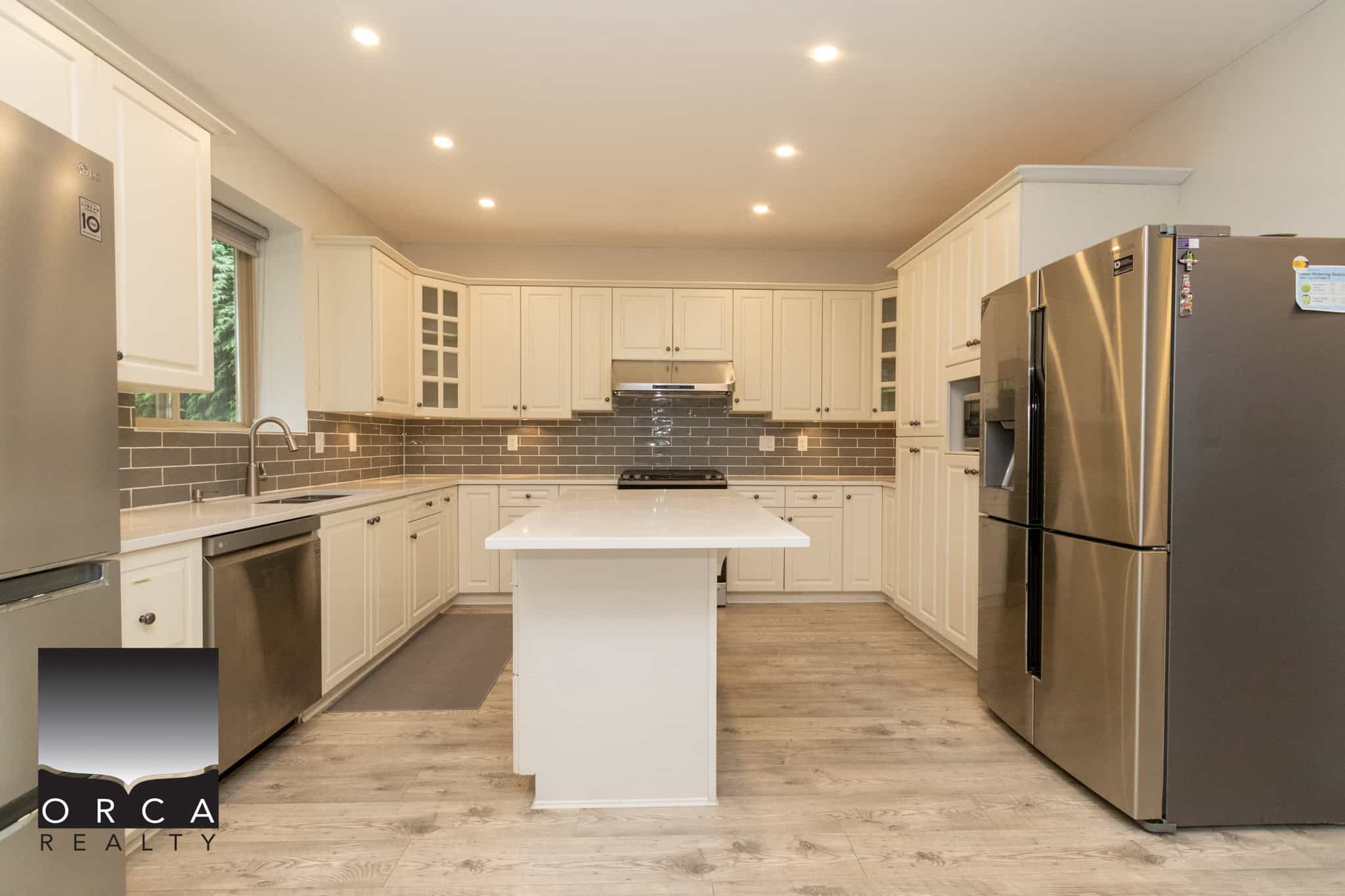 Bright modern kitchen with white cabinetry, stainless steel appliances, and grey subway tile backsplash, perfect for stylish Vancouver Island homes.