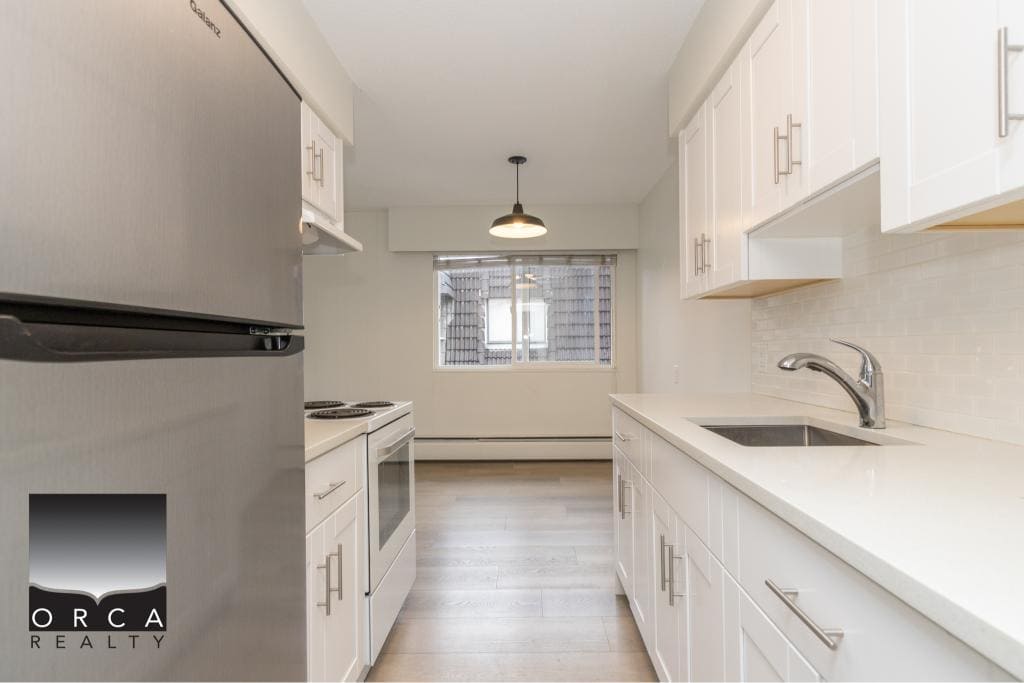 Modern white kitchen with stainless steel appliances, bright lighting, and clean design, ideal for Toronto homebuyers and real estate investors.