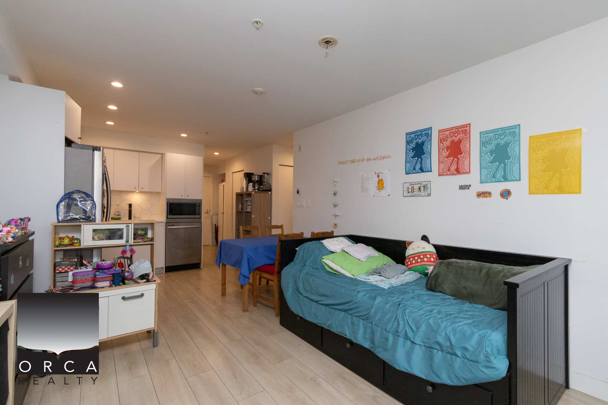 Convertible sofa bed in a modern, open-concept living space with a dining table, colorful wall art, and a cozy family area, ideal for Vancouver Island real estate listings.