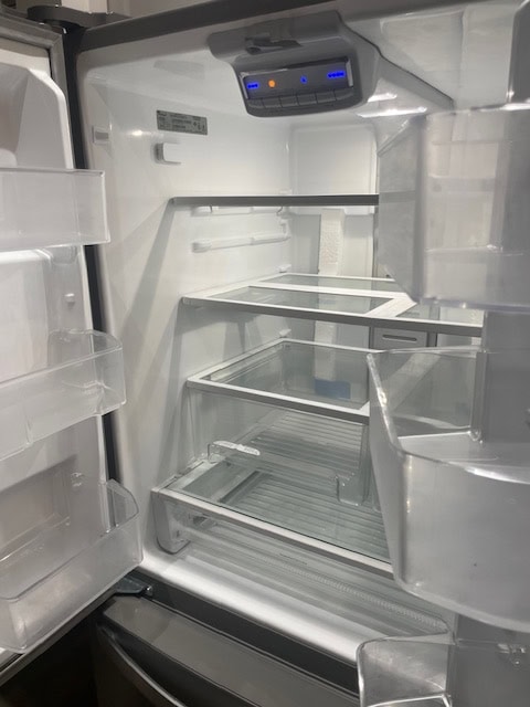 Open modern stainless steel refrigerator with empty shelves, ideal for home or real estate staging in Ontario, Canada.