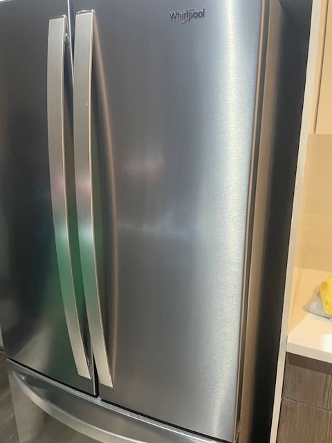 Stainless steel Whirlpool refrigerator in a modern kitchen setting.