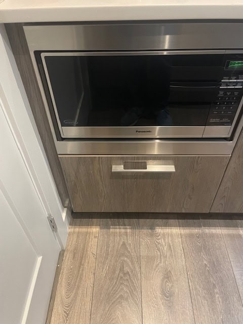 Stainless steel microwave oven integrated into kitchen cabinetry, modern appliance in a contemporary kitchen setting.
