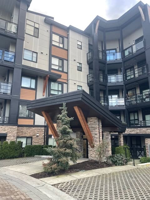 Modern condominium building with landscaped entrance in Vancouver, BC, showcasing contemporary architecture and stylish balconies, ideal for real estate investments and luxury living.