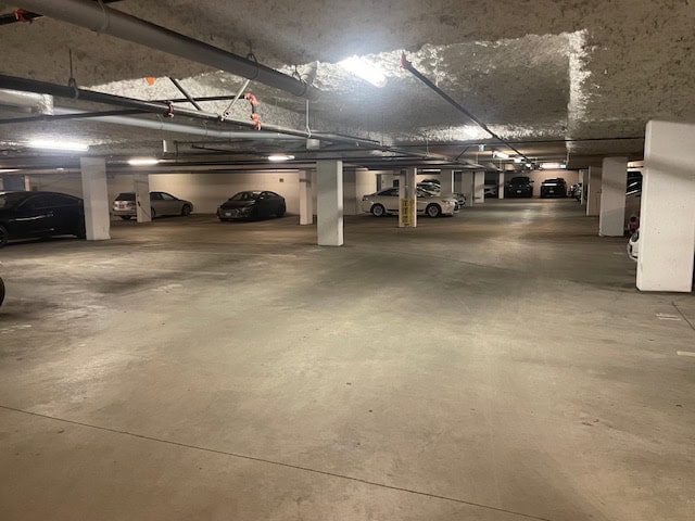 Underground parking garage with multiple parked cars and concrete pillars, offering convenient and secure parking solutions.