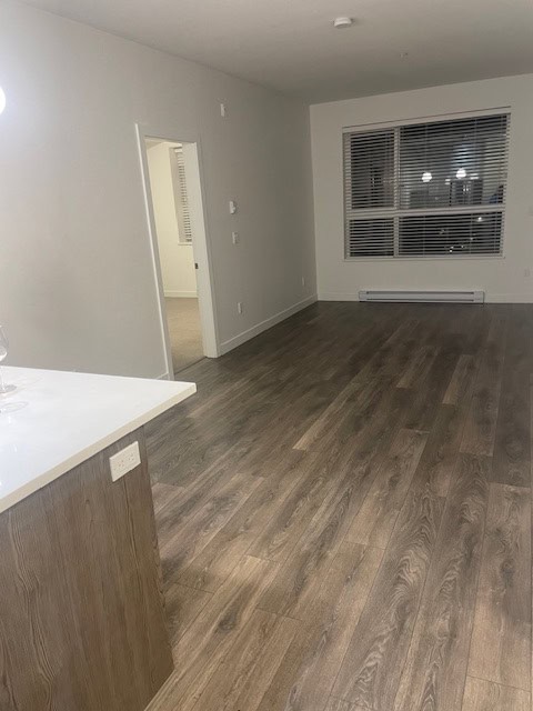 Modern apartment interior with hardwood flooring and large window showcasing city views in Vancouver, BC. Perfect for buyers seeking a stylish living space in a vibrant community.