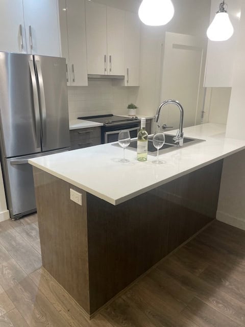 Modern kitchen with white cabinetry, stainless steel appliances, and a sleek island - ideal for Vancouver real estate buyers.
