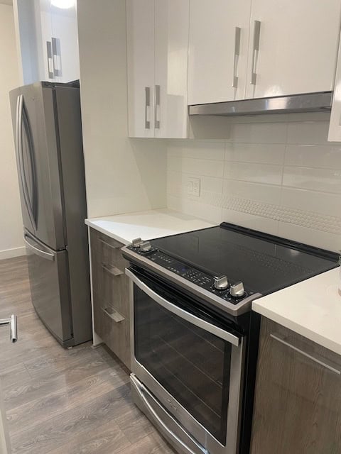 Modern stainless steel refrigerator and electric oven in a contemporary kitchen with white and grey cabinetry, ideal for Vancouver real estate and property listings by Orca Realty Inc.