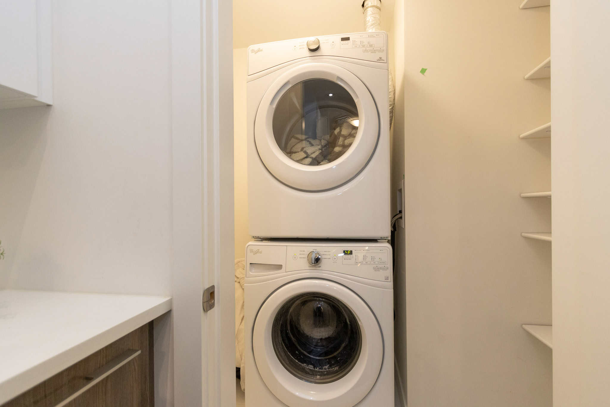 Stacked washer and dryer in a laundry closet at Orca Realty Inc. offering convenient home styling and property management services in BC.