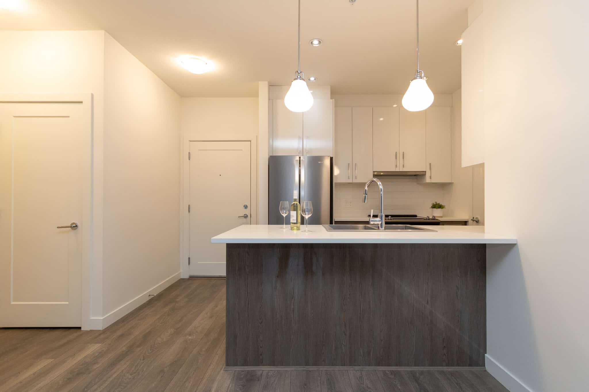 Modern kitchen with white cabinetry, stainless steel appliances, and a sleek island for entertaining, showcasing a contemporary home design by Orca Realty Inc. in Vancouver, BC.