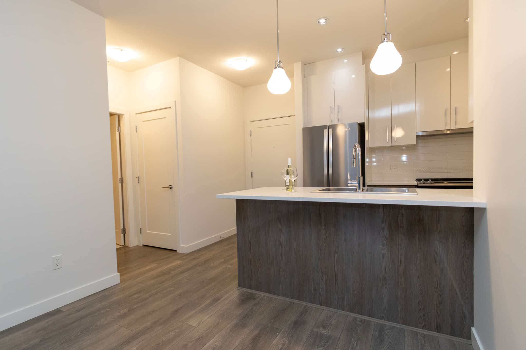 Modern kitchen with stainless steel appliances and white cabinetry, bright open-concept design, ideal for Vancouver Island living and real estate investment.