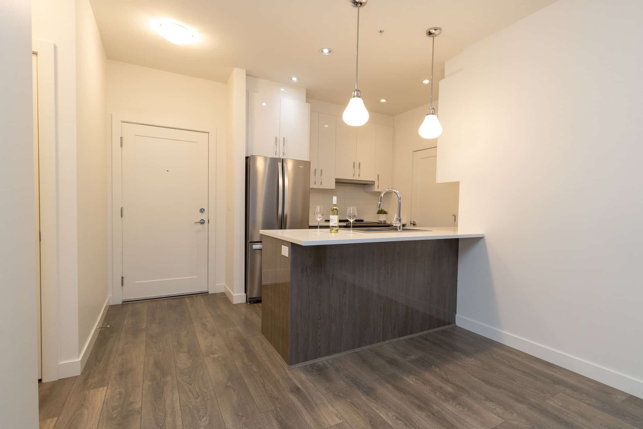 Modern open-concept kitchen in Vancouver with stainless steel appliances, white cabinetry, and stylish pendant lighting for downtown condo living.