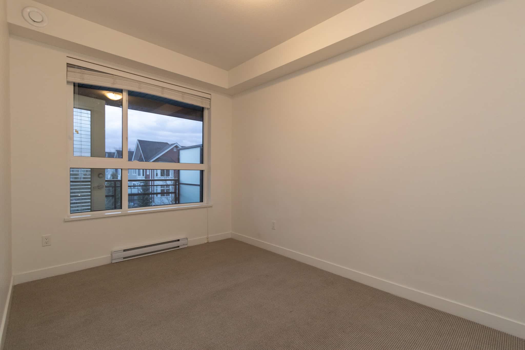Bright modern bedroom with large window and neutral carpet, ideal for Vancouver area homes; perfect for comfortable living and home staging.