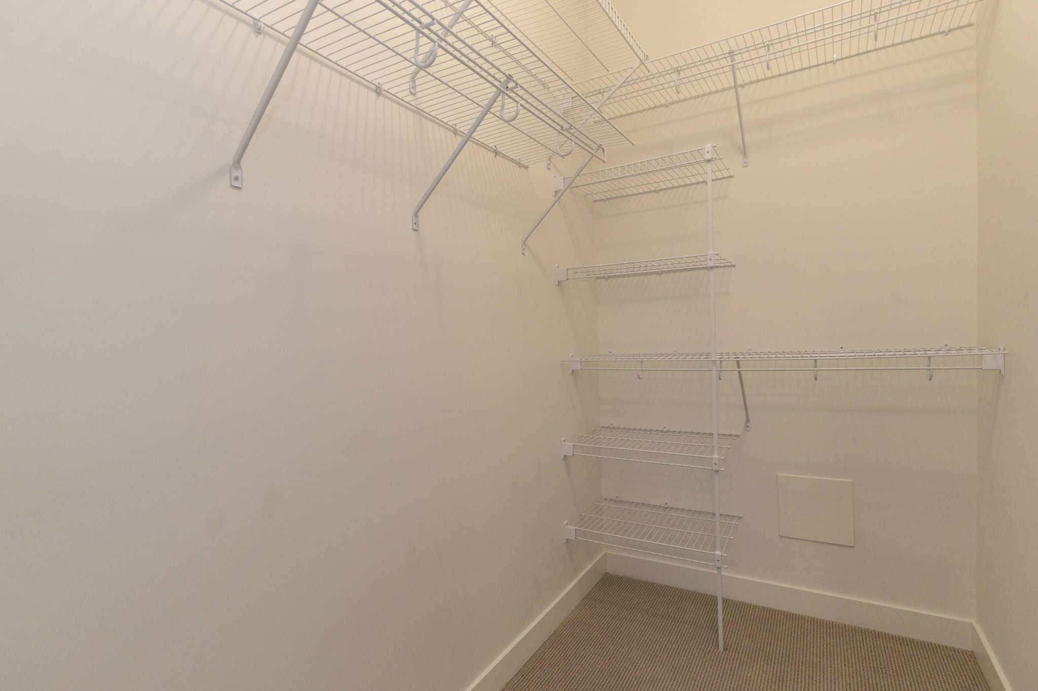 Spacious walk-in closet with white wire shelving for organized storage and easy access. Perfect for modern homes, featuring ample space for clothing, shoes, and accessories.