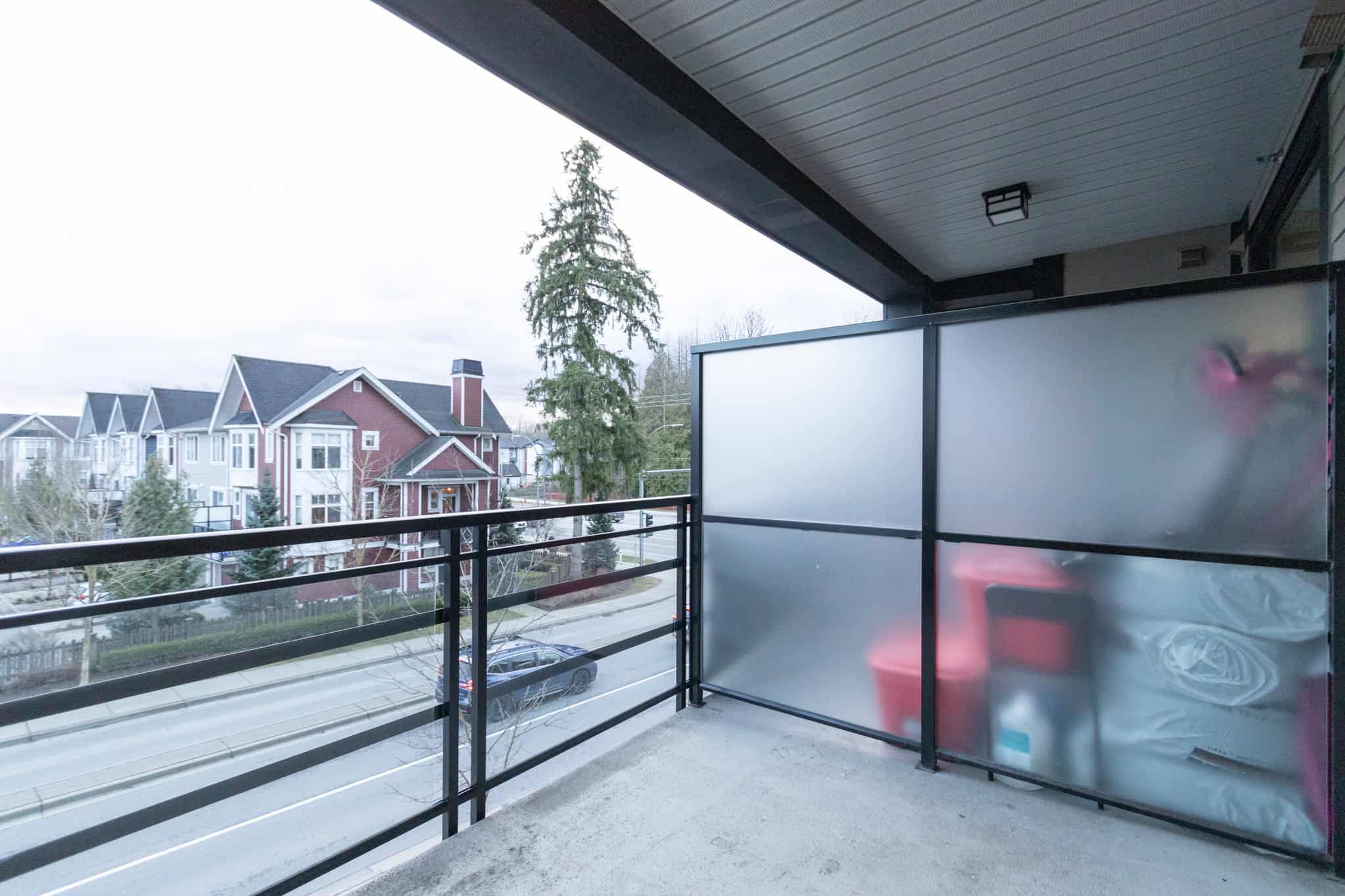 Spacious balcony overlooking a residential neighbourhood with modern houses in the background, ideal for relaxing or outdoor living in Vancouver.