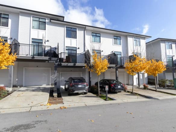 Modern townhouse complex with private garages and balconies, features vibrant autumn trees, perfect for Vancouver real estate investments or property purchases.