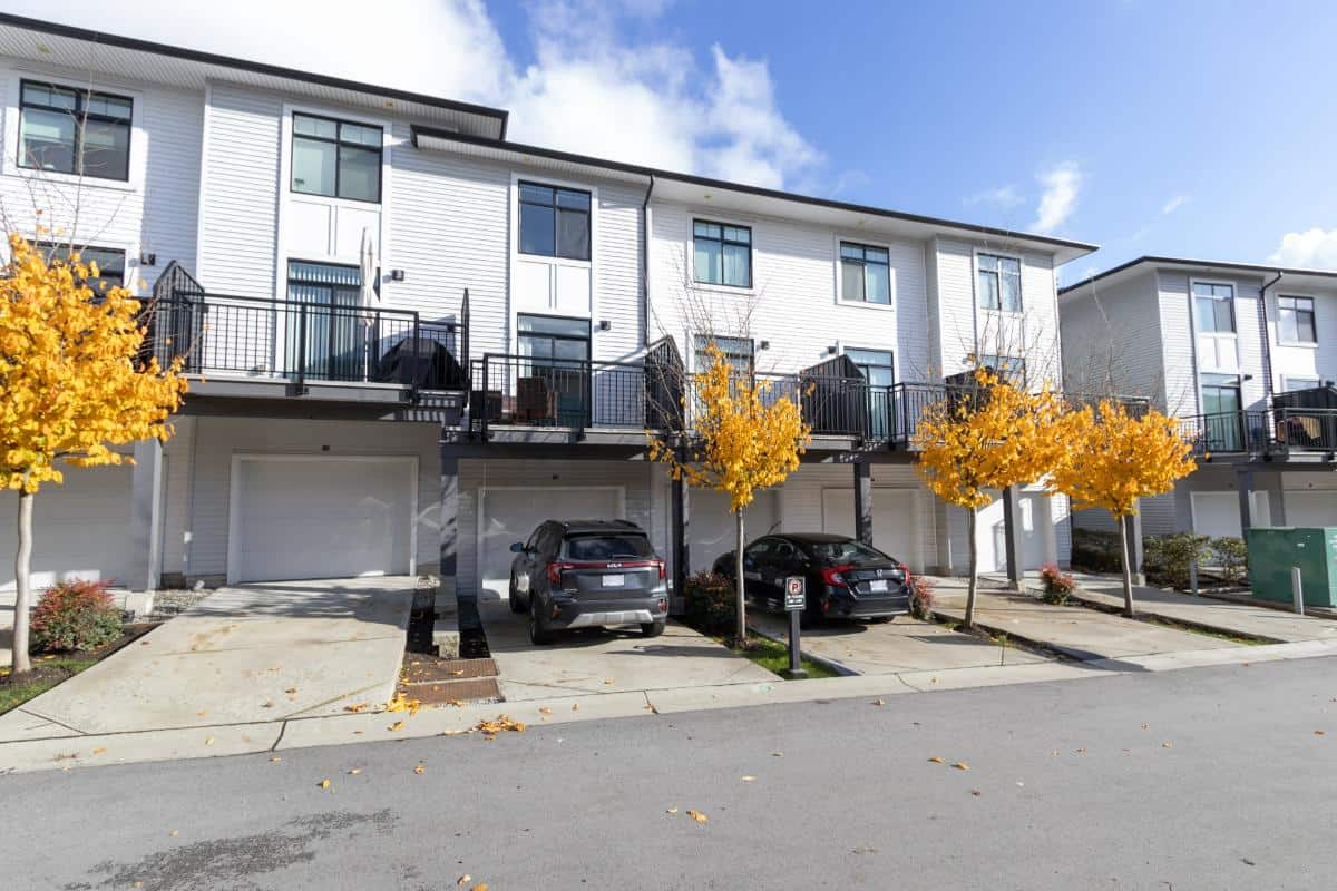 Modern townhouse complex with private garages and balconies, features vibrant autumn trees, perfect for Vancouver real estate investments or property purchases.