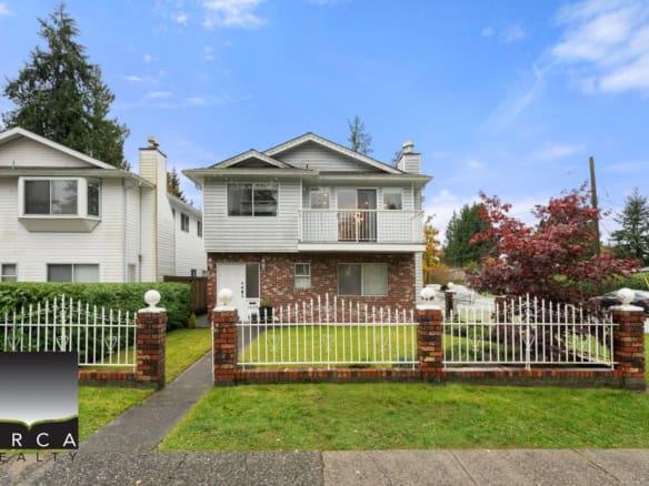 Charming Vancouver home with brick facade, manicured lawn, white picket fence, and surrounding mature trees, perfect for real estate investors and families seeking a cozy, classic residence.