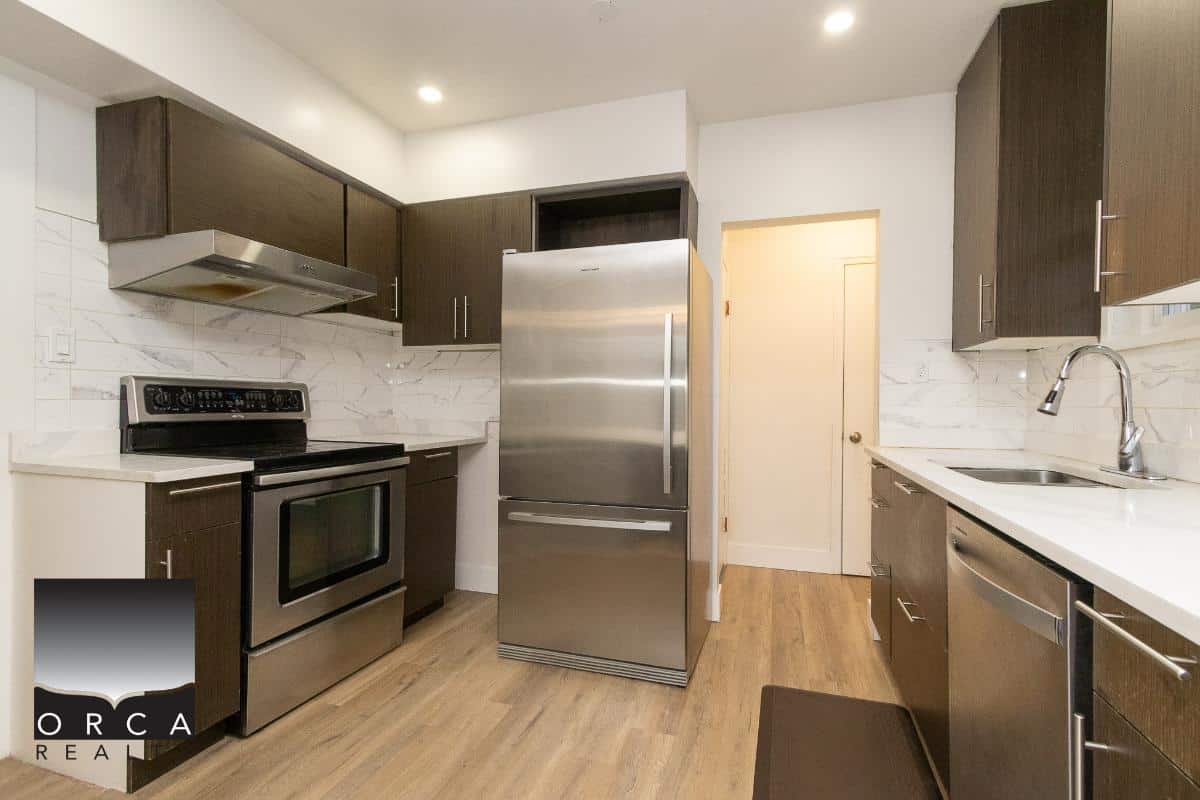 Contemporary kitchen with stainless steel appliances, dark wood cabinets, and white marble backsplash, perfect for modern Vancouver Island homes.