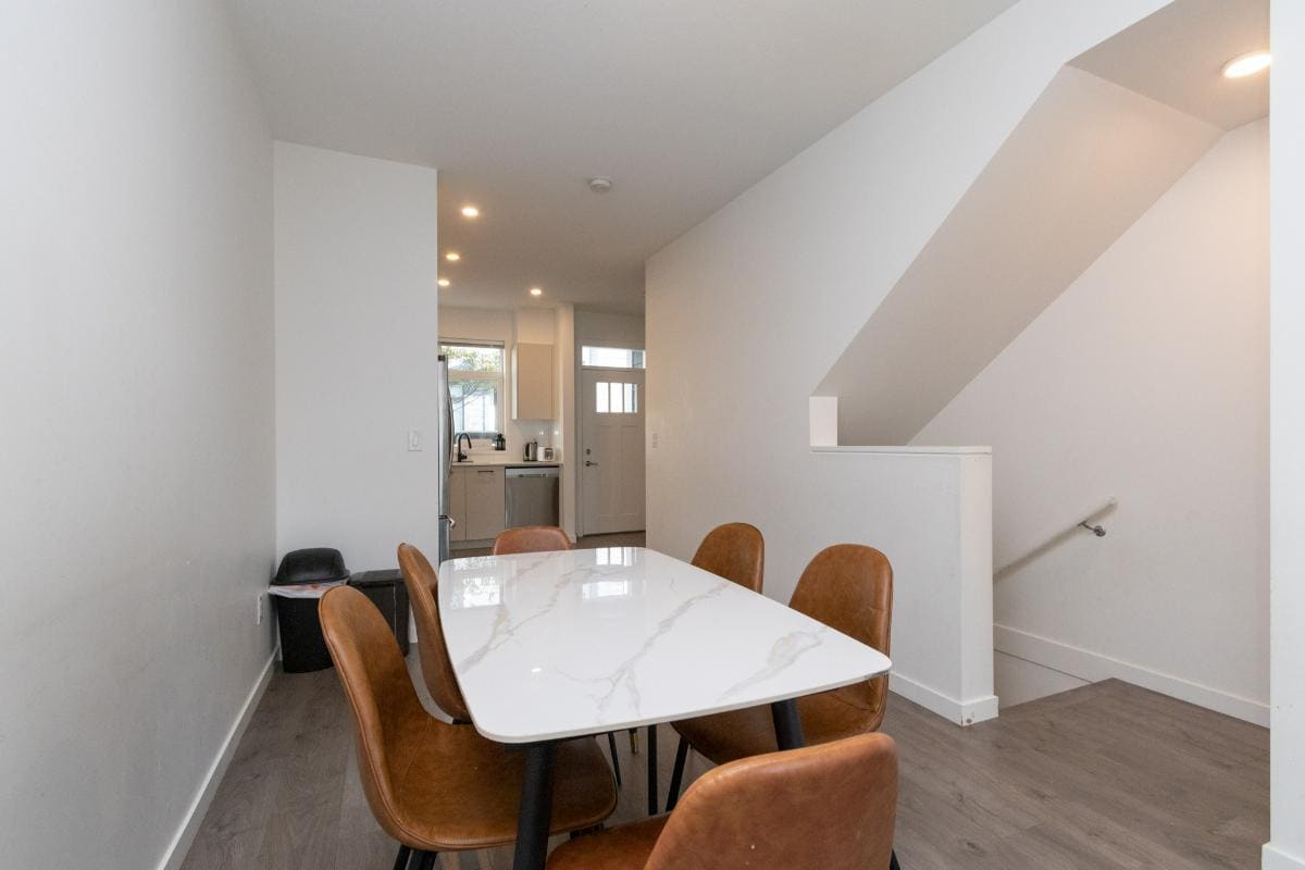 Modern dining area with white marble table and brown leather chairs in a contemporary home interior.