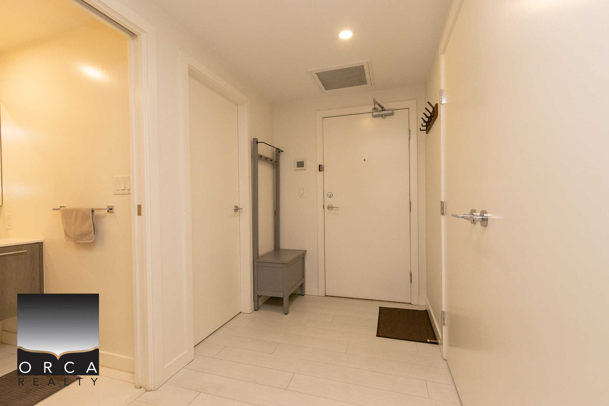 Bright and inviting apartment entryway with neutral-toned walls and flooring, featuring a coat rack and modern design elements.