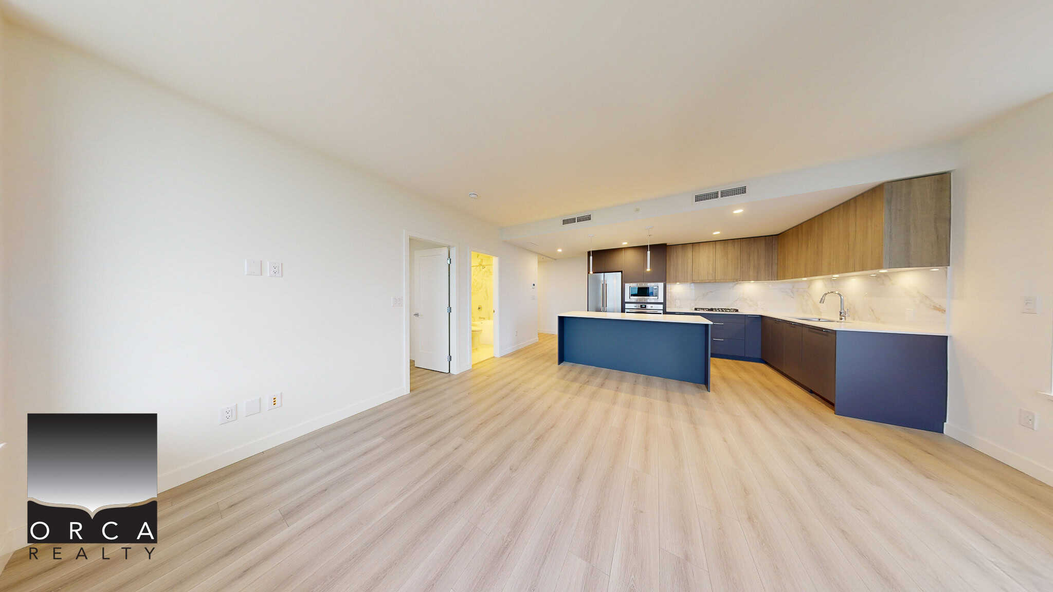 Modern open-concept kitchen and living space in a contemporary condo, featuring sleek blue cabinets, a spacious island, and elegant wood accents, ideal for Vancouver real estate buyers.