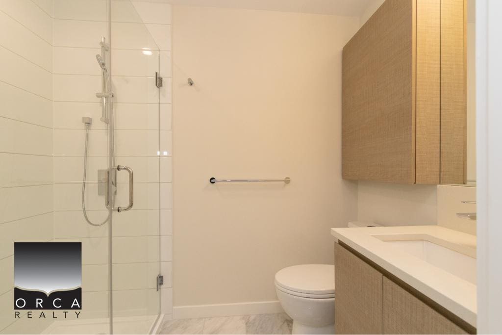 Bright modern bathroom with walk-in shower, neutral tones, and stylish cabinetry, available through Orca Realty Inc., your local real estate experts.