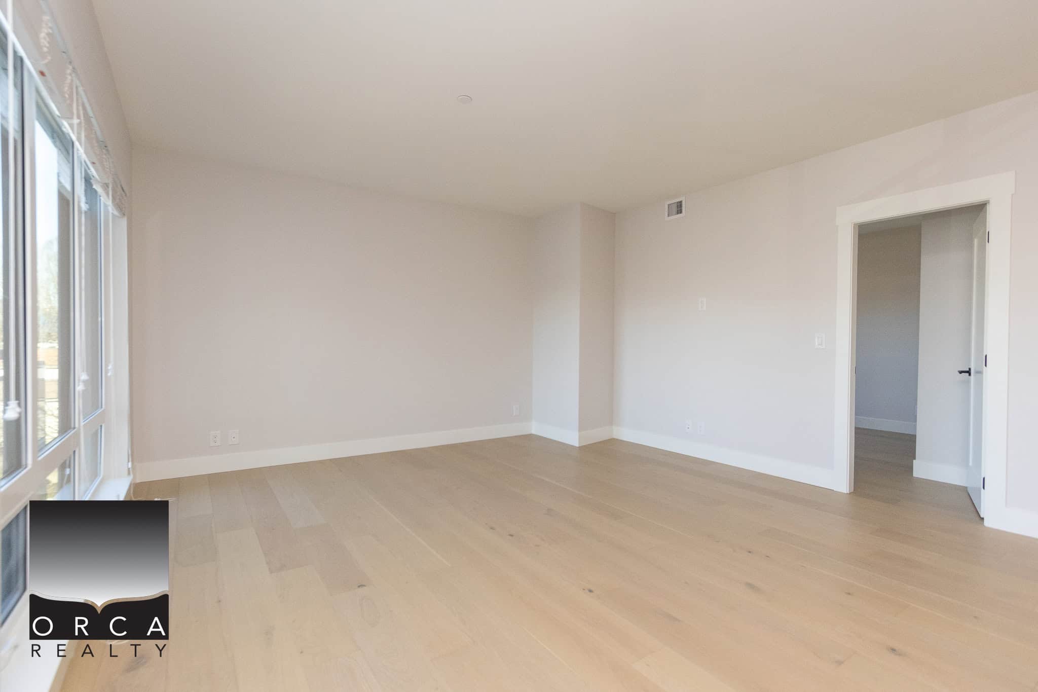 Bright and spacious empty living room with large window, light hardwood floors, neutral wall color, and modern interior design, perfect for Toronto real estate buyers.