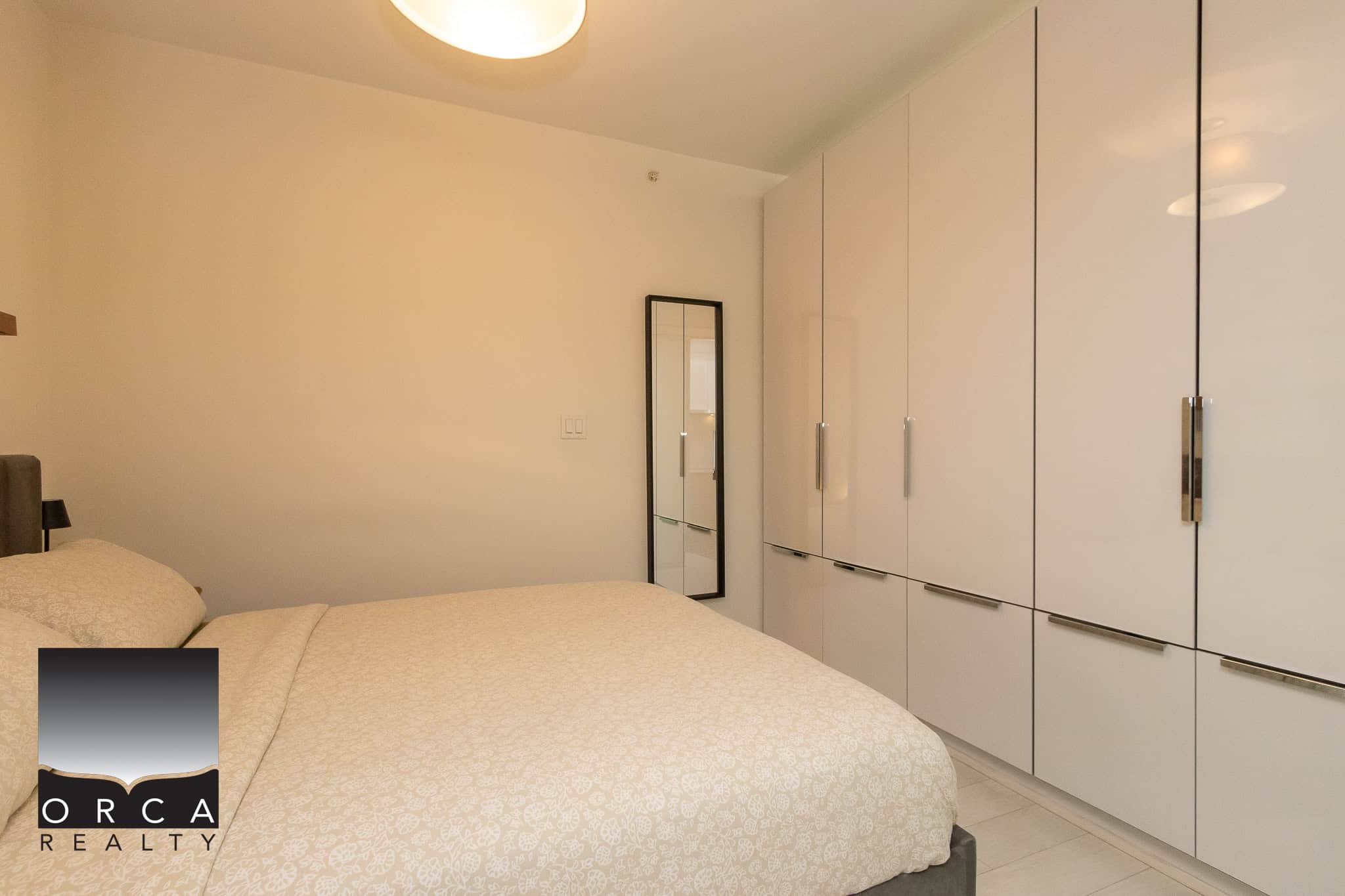Modern bedroom with white cabinetry, minimalist decor, and bright lighting, showcasing Orca Realty Inc.'s real estate listings in Vancouver, BC. Perfect for clients seeking contemporary living spaces.