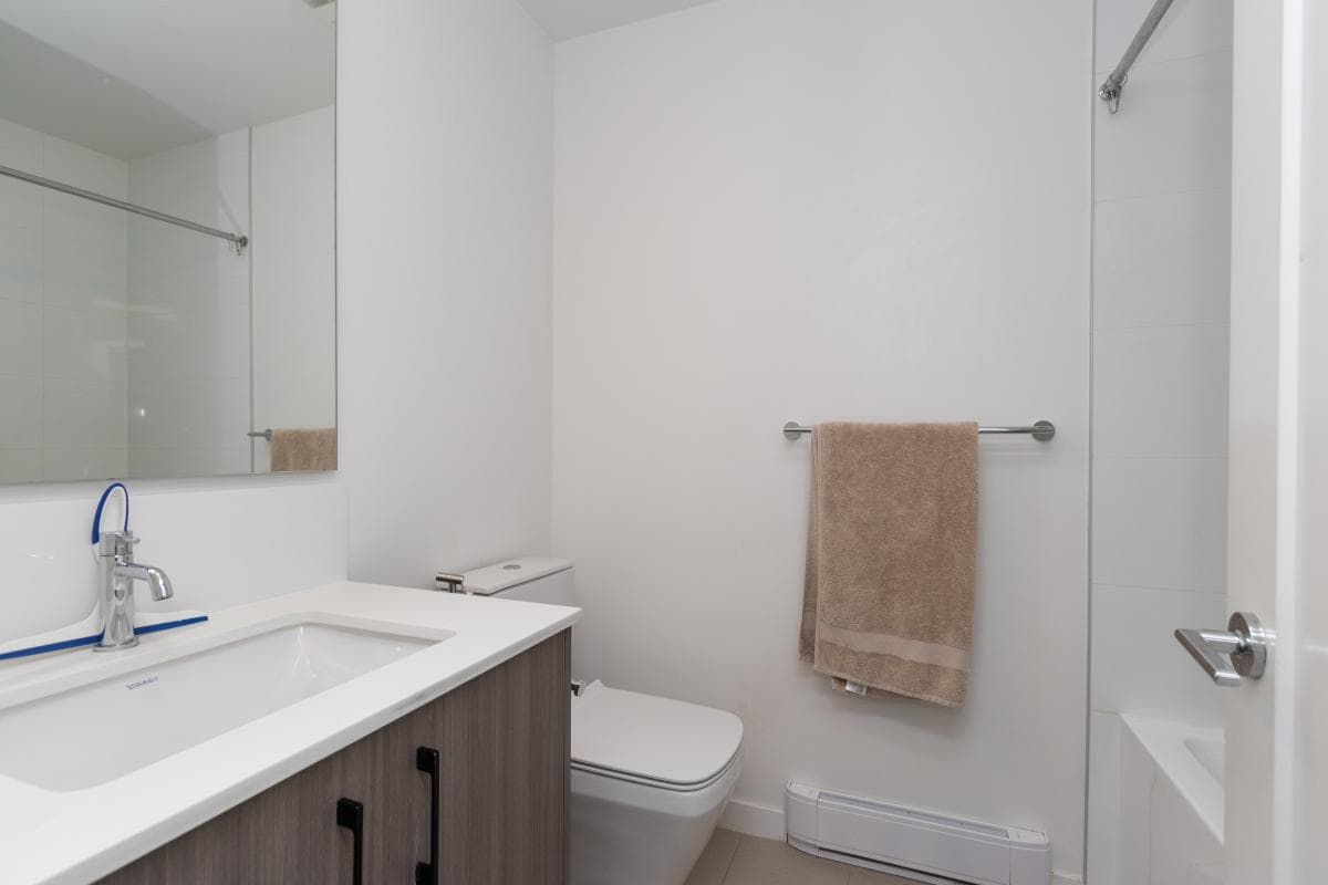 Modern bathroom with white walls and minimalist design, featuring a sleek vanity, toilet, and towel rack, ideal for contemporary Vancouver real estate and property listings.