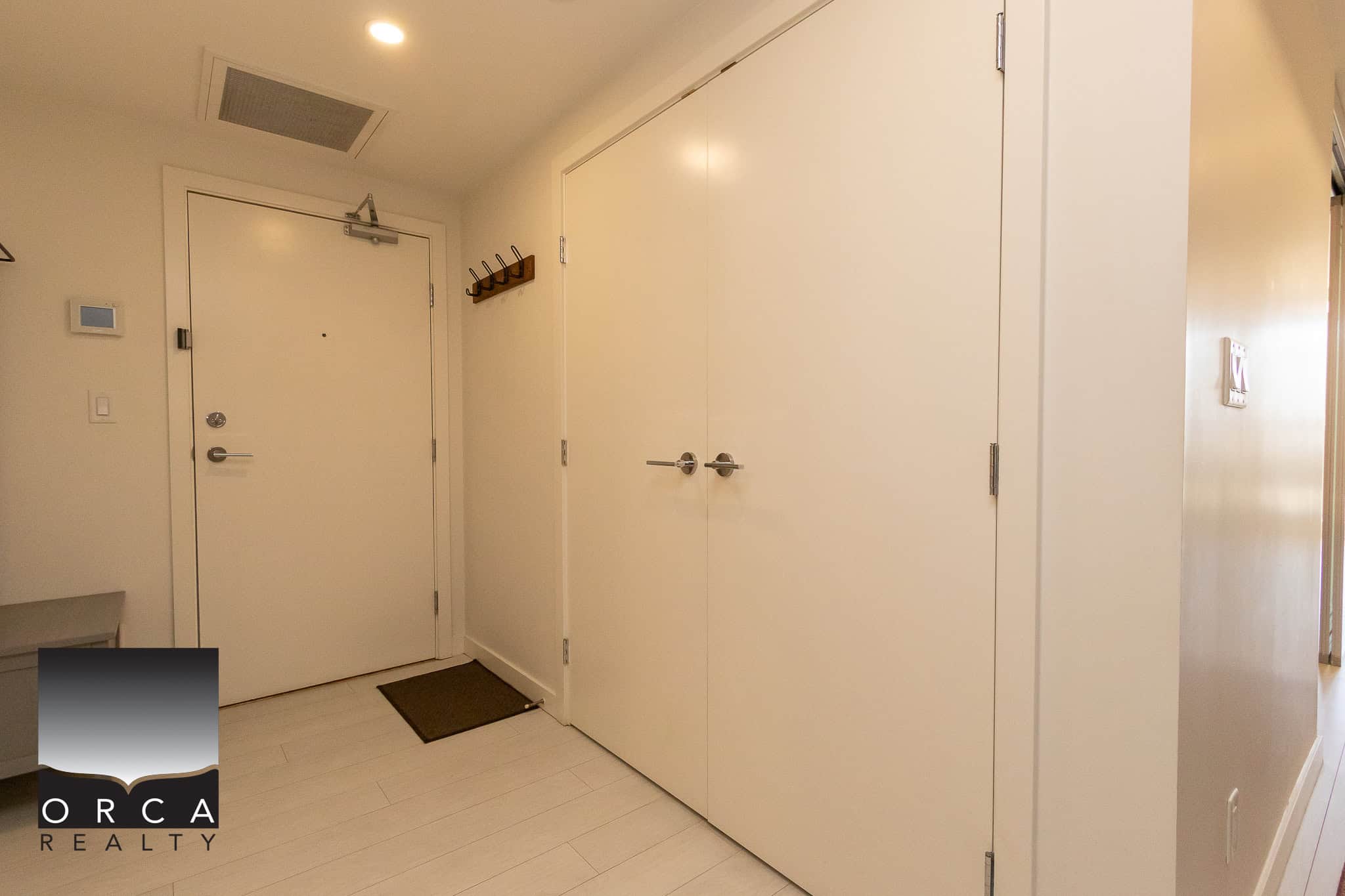 Modern residential entryway with clean white walls, wooden accents, and ample closet storage, ideal for Vancouver area homes and real estate listings.