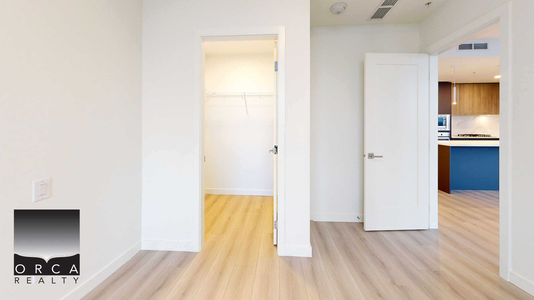 Bright modern interior showcasing an open concept living space, with white walls, light wood flooring, and seamless access to the kitchen area for a spacious and airy feel.