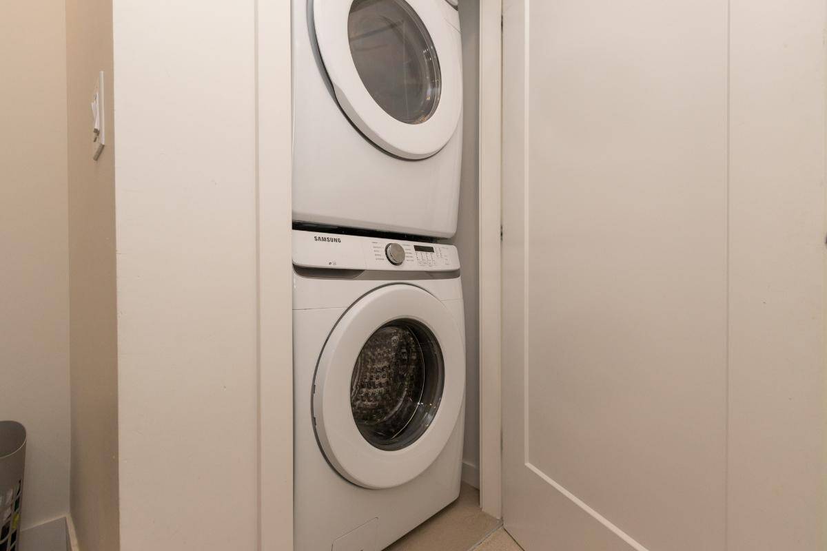Stacked washer and dryer in a small laundry closet, ideal for efficient home utility spaces in Vancouver, BC. Perfect for condo or apartment living, showcasing modern laundry appliances.