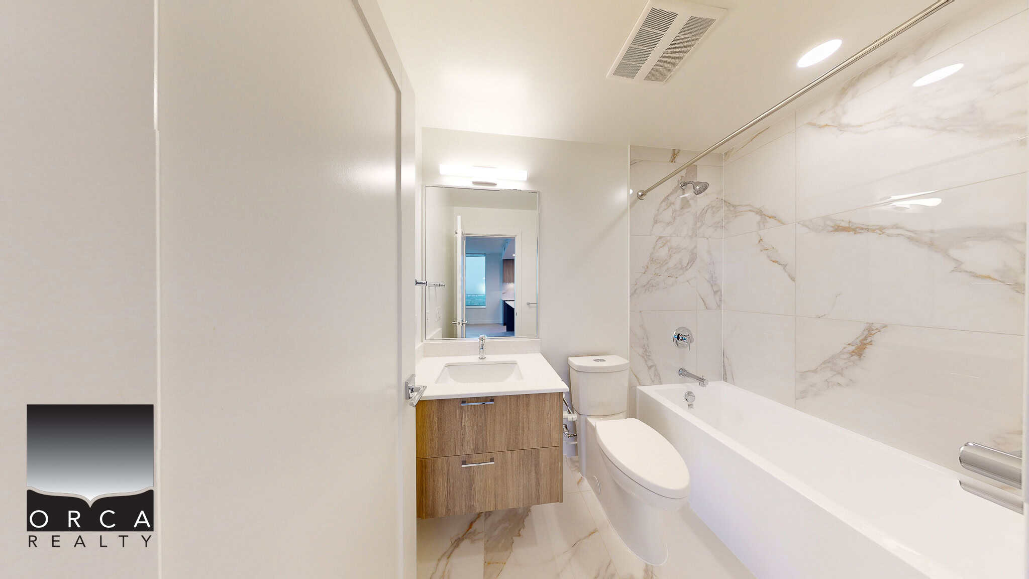 Modern bathroom featuring a marble-tiled bathtub, sleek vanity, and contemporary fixtures, ideal for residential real estate listings by Orca Realty Inc.