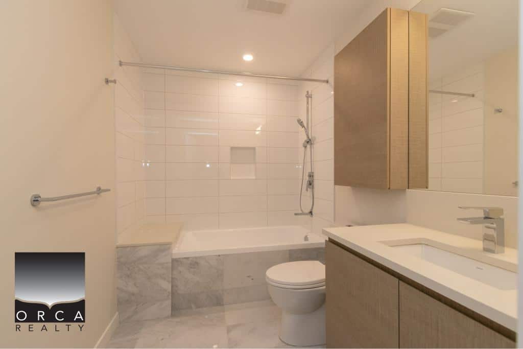 Modern bathroom with white tile accents, sleek vanity, and walk-in shower, showcasing contemporary interior design for Vancouver real estate.