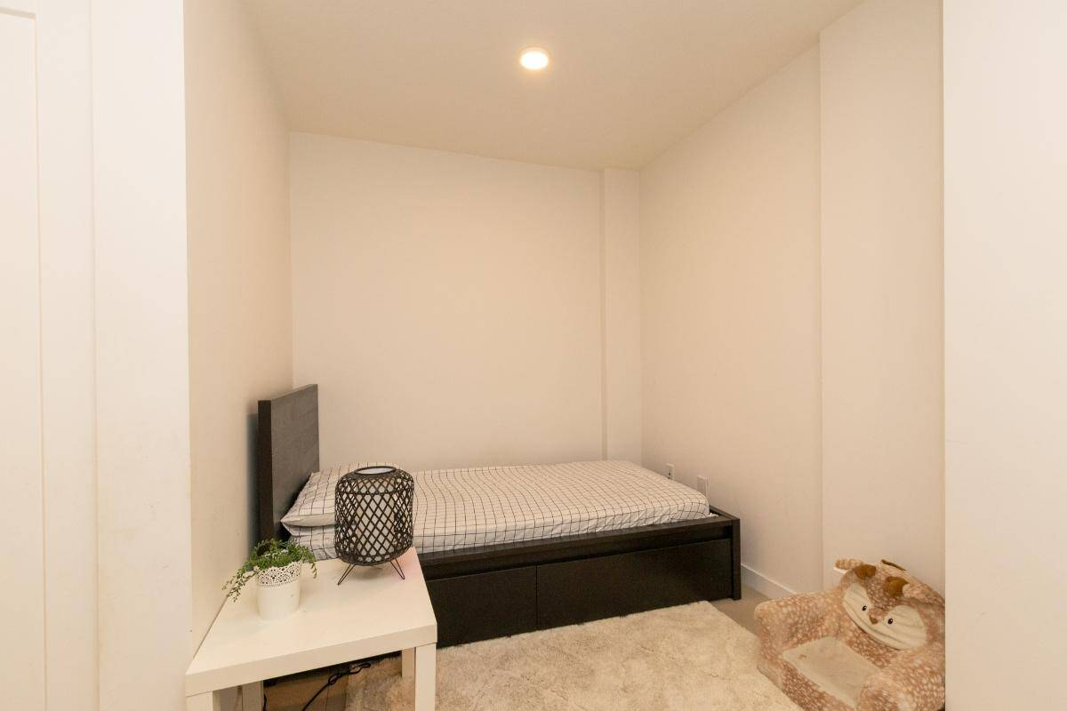 Cozy minimalist bedroom with black bed frame, white nightstand, and plush animal pet bed in a modern home in Vancouver, BC.