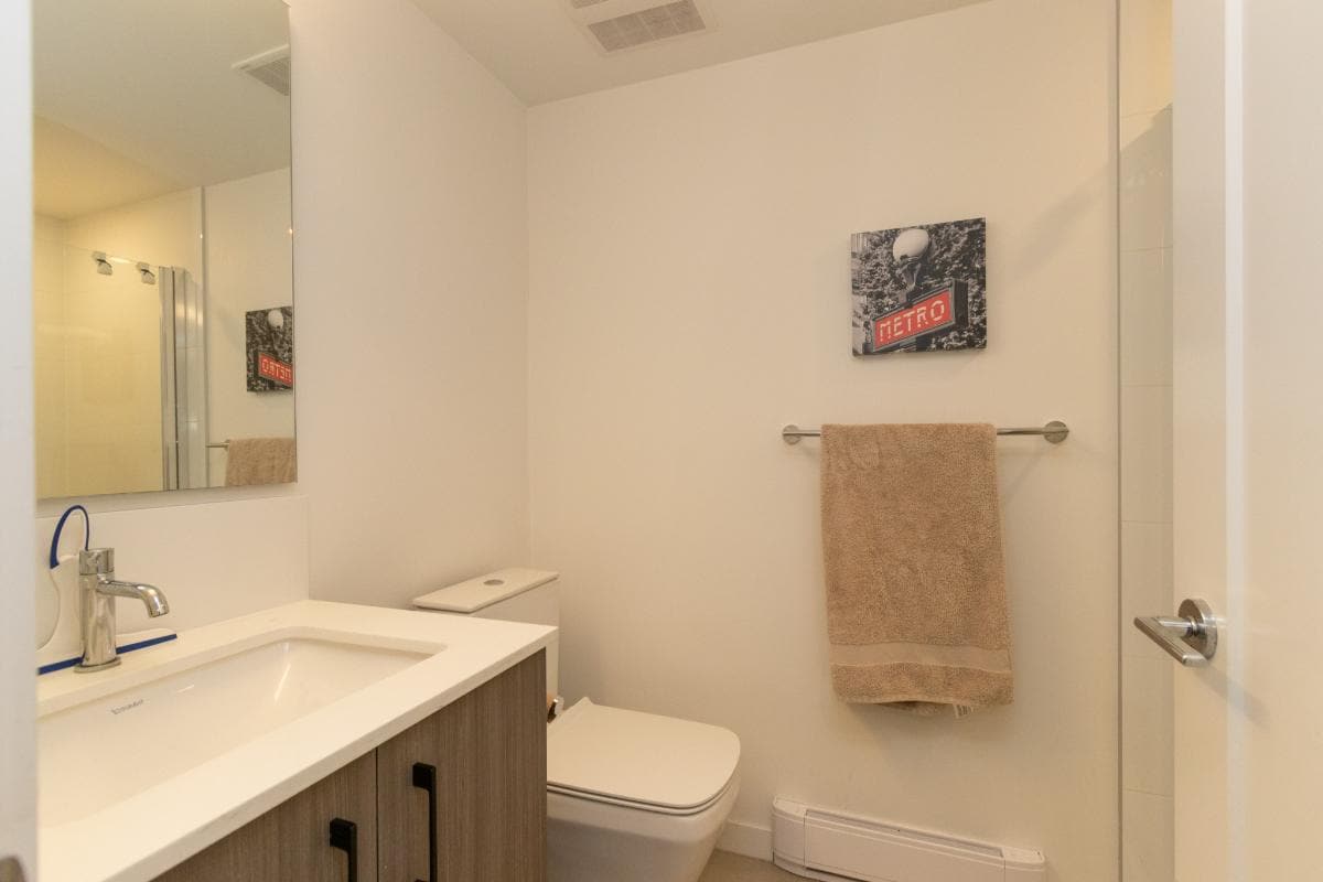 Modern bathroom design featuring a sleek white sink vanity, wall-mounted toilet, and contemporary decor, perfect for Vancouver Island homes. Discover this beautiful property with Orca Realty Inc.