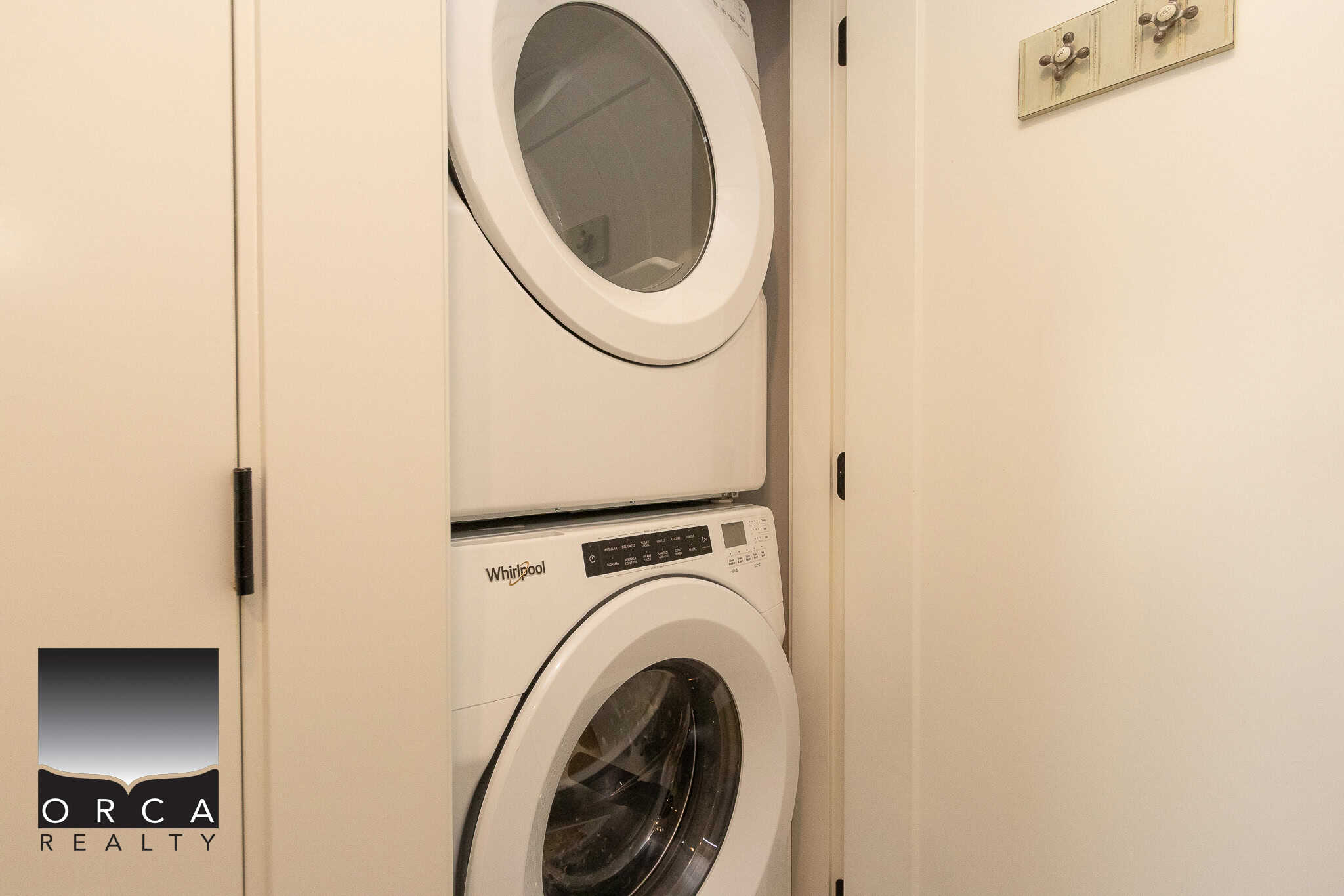Stacked white washing machine and dryer in a compact laundry closet in a modern home, ideal for small space living.